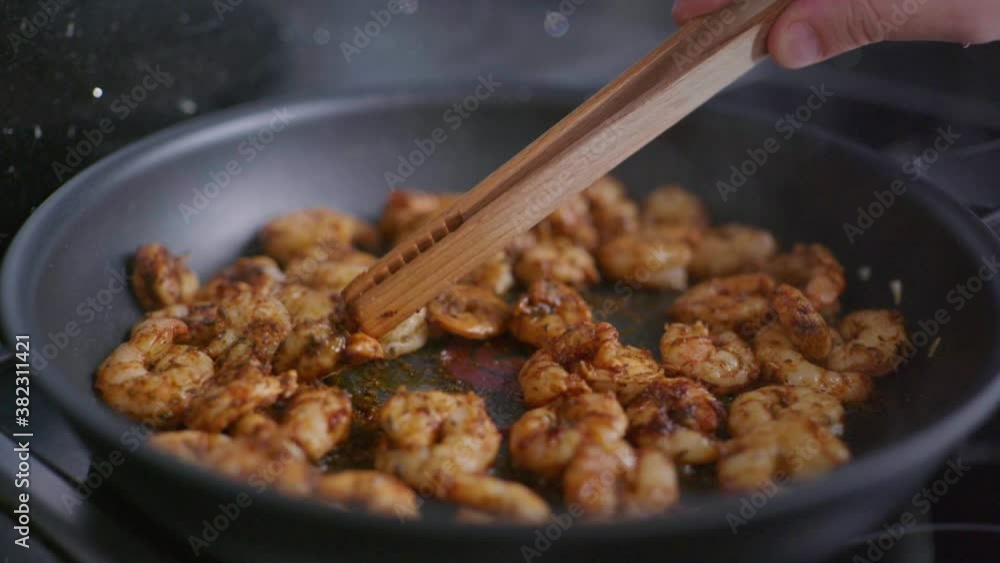 Close-up slow motion shot of gently turning prawns in a frying pan with cajun seasoning. Close-up slow motion shot of gently turning prawns in a frying pan with cajun seasoning.