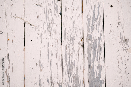 The texture of wooden planks with white peeled paint.