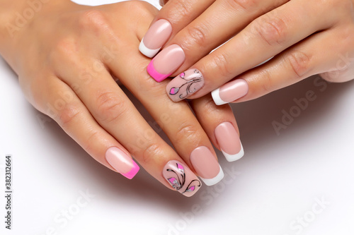 Gel nail design. French pink-white manicure with drawings  flowers and monograms on short square nails close-up on a white background.
