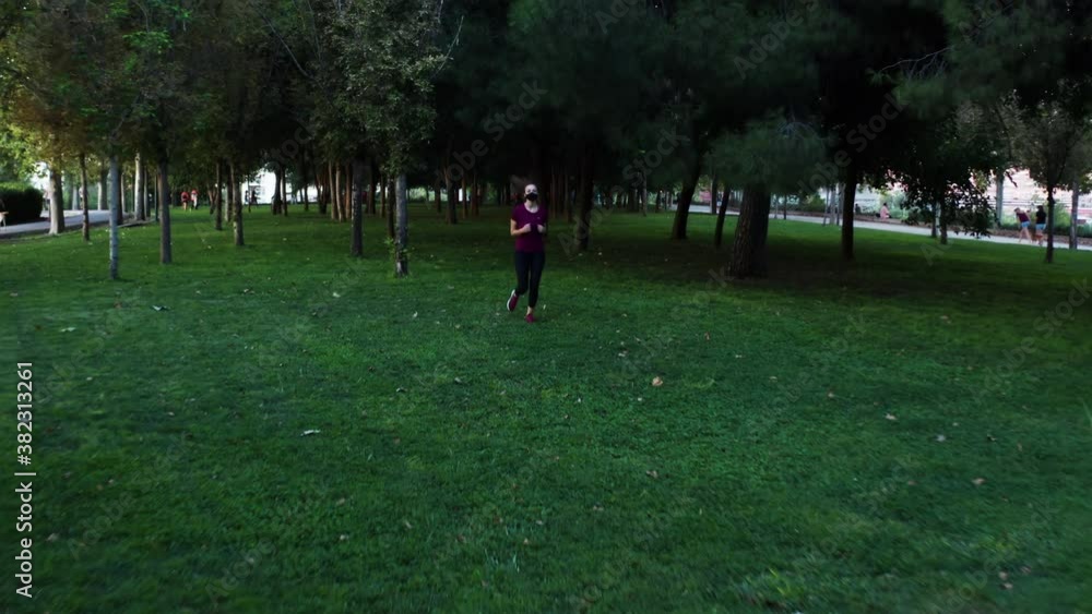 A woman in mask running towards the camera in Enrique Tierno Galván Park. A woman in mask running towards the camera in Enrique Tierno Galván Park.
