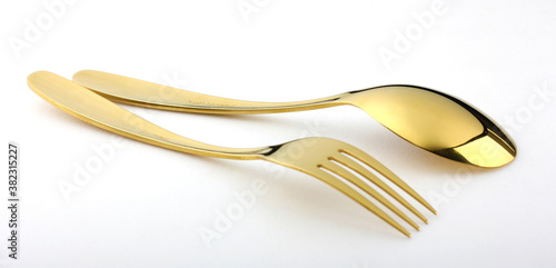 Elegant and expensive golden spoon and fork are placed on a white background.