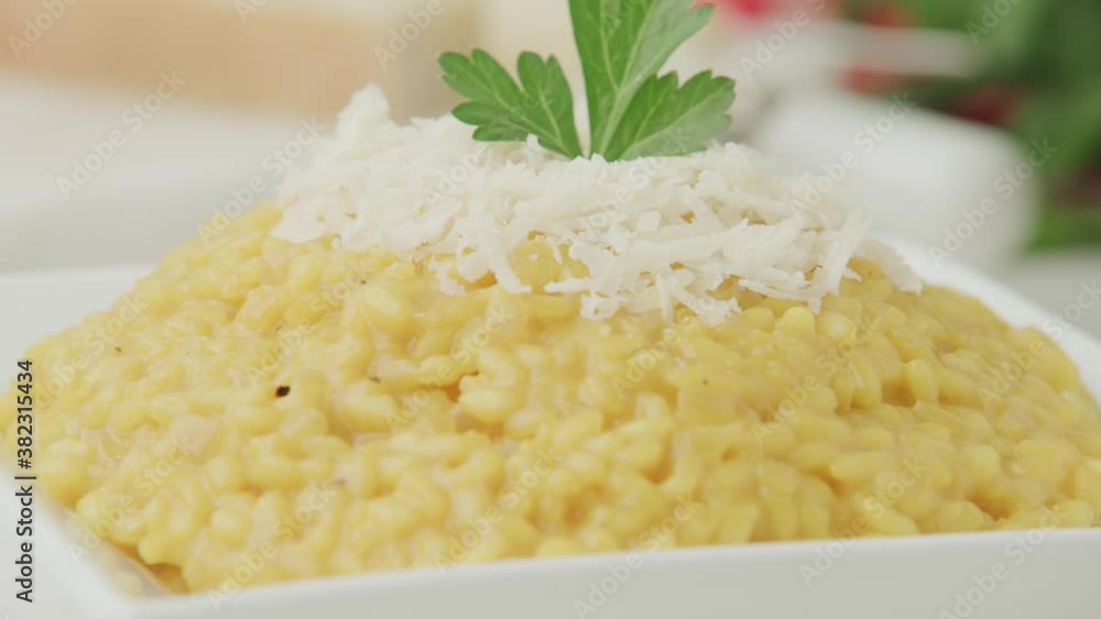 A Serving Of Creamy Risotto In A Plate Topped With Grated Parmesan Cheese And Parsley - tilt down shot A Serving Of Creamy Risotto In A Plate Topped With Grated Parmesan Cheese And Parsley - tilt down shot