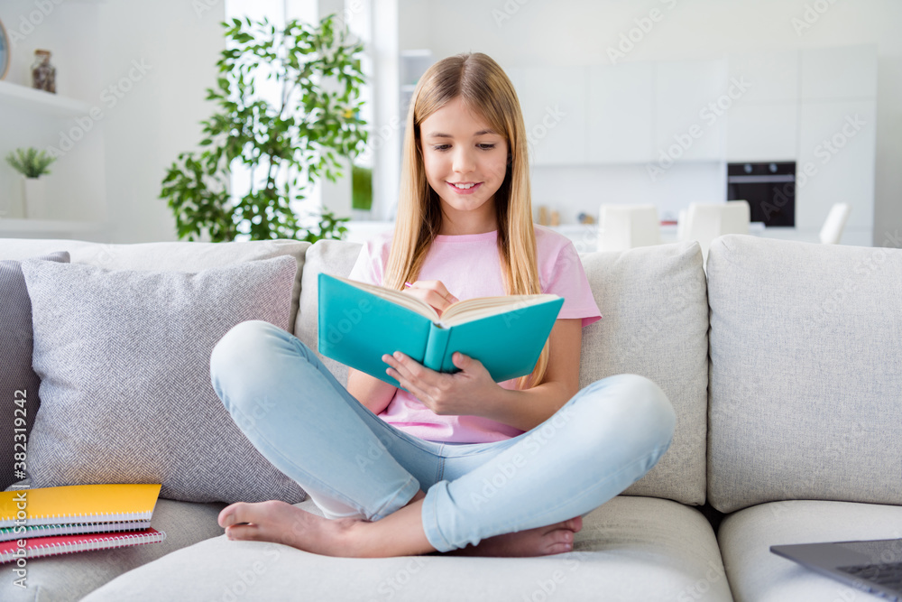 Dear diary. Full length photo of positive kid girl sit divan legs crossed write home task in copy book pencil wear t-shirt denim jeans in house indoors room Dear diary. Full length photo of positive kid girl sit divan legs crossed write home task in copy book pencil wear t-shirt denim jeans in house indoors room