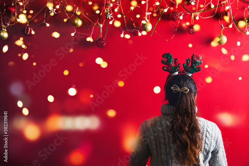 Christmas New Year. Young Woman dressed in warm sweater with  Props ball red with christmas ornaments in Holiday on shine red background. Concept merry christmas.