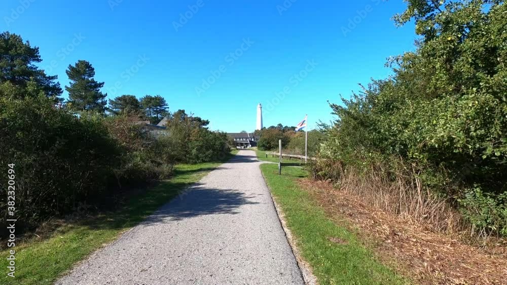 White lighthouse of Schiermonnikoog with the local flag waving across the road White lighthouse of Schiermonnikoog with the local flag waving across the road