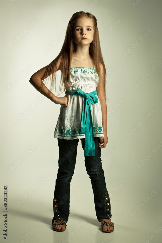Beautiful girl blonde child schoolgirl in a white tunic and black trousers in the studio on a white background Beautiful girl blonde child schoolgirl in a white tunic and black trousers in the studio on a white background