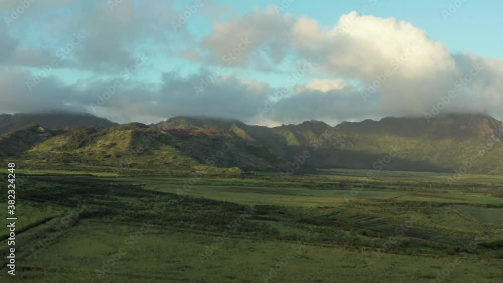 Kauai Haupu Ridge aerial drone view over green fields at sunset. Framland and mountain landscape in background Poipu Hawaii Kauai Haupu Ridge aerial drone view over green fields at sunset. Framland and mountain landscape in background Poipu Hawaii