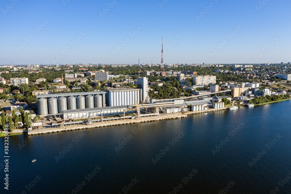 Obraz premium Grain elevator and silos near the river aerial view.