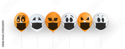Colored balloons with faces in medical mask for Halloween party on white background. Space for text. Happy holiday October 31. Halloween celebration concept in the midst of covid-19 and coronavirus