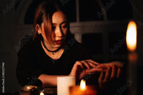 Witch doing palm reading from human hand.