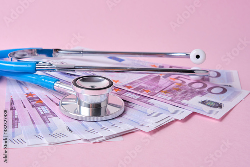 Фотография stethoscope and euro banknotes on a pink background, a symbol of stability, grow