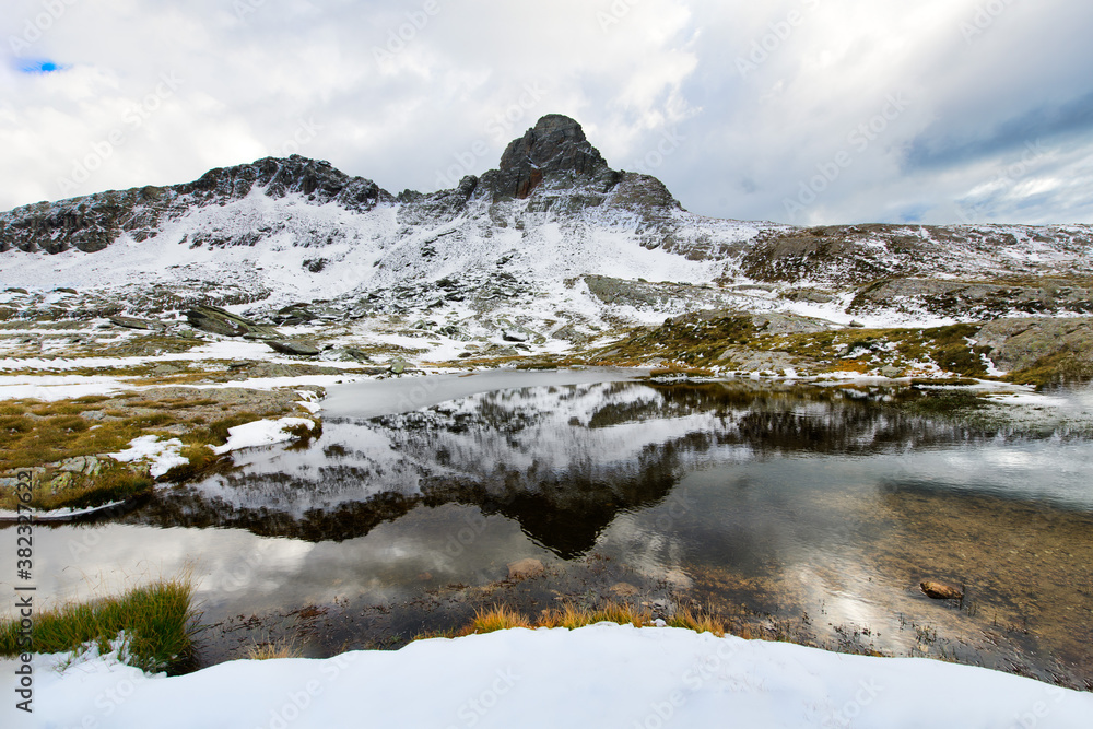 Idyllic mountain lake with reflection of the top with the first autumn snow
