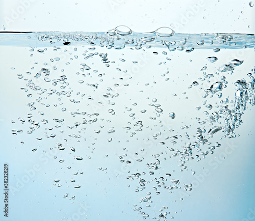 Close up of clean blue water and splash with bubbles of air isolated on white background. Diet, health and nature concept. Copy space..