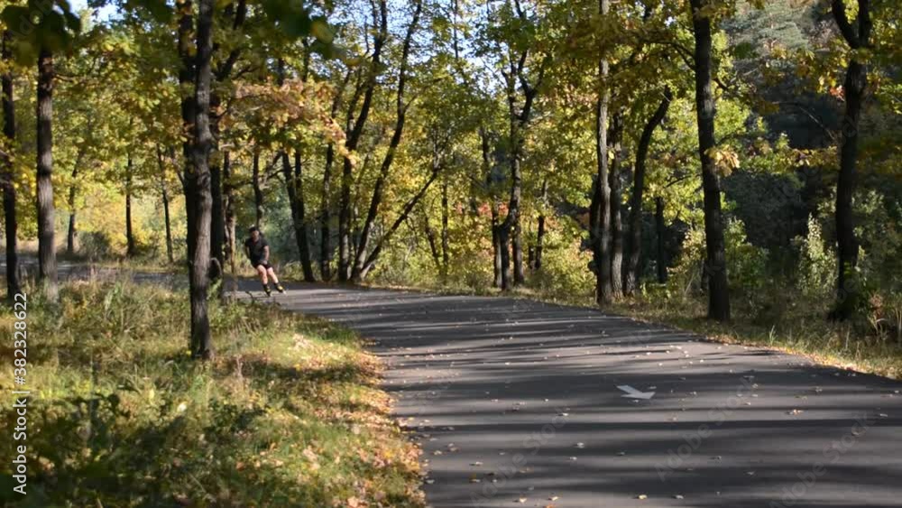 A man is rollerblading on an asphalt track in the autumn forest. A man is rollerblading on an asphalt track in the autumn forest.
