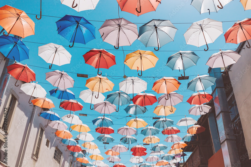 Pedestrian street with colorful multi-colored umbrellas as decoration and protection from the bright sun at noon.