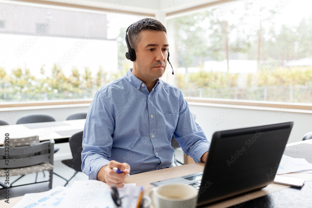 remote job, technology and business concept - middle-aged man with headset and laptop computer having conference call at home office