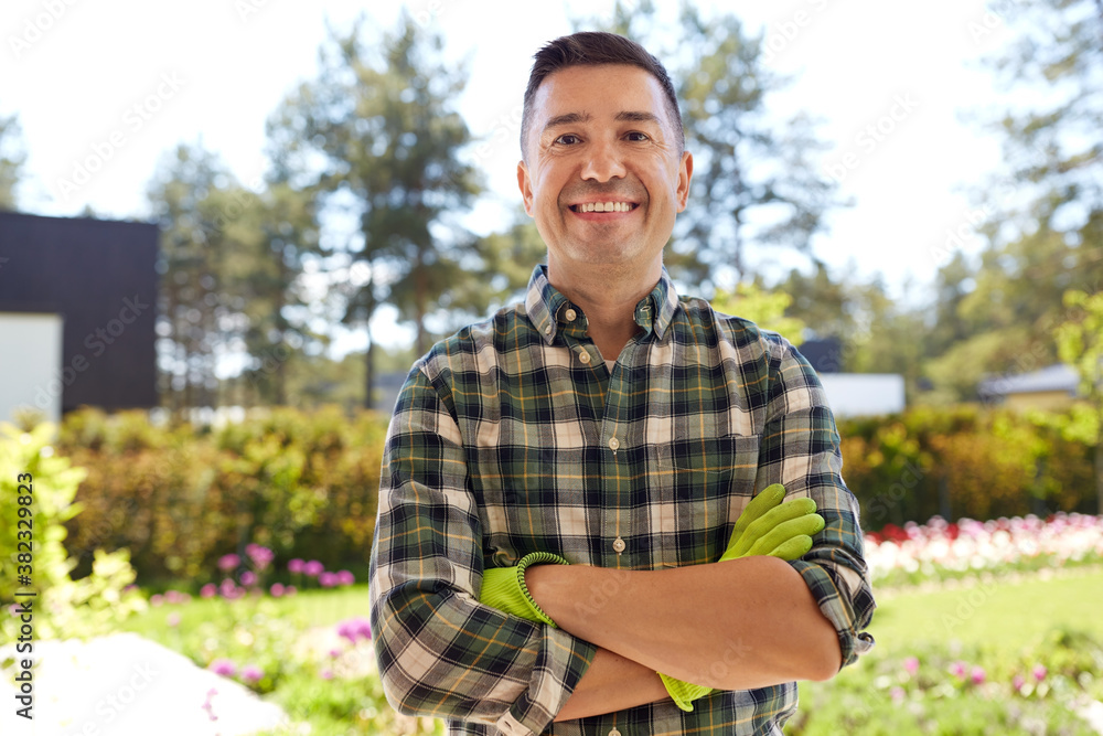 gardening and people concept - portrait of happy smiling middle-aged man with crossed arms in gloves at summer garden gardening and people concept - portrait of happy smiling middle-aged man with crossed arms in gloves at summer garden
