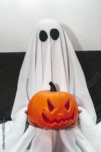Portrait of person dressed as ghost for halloween holding big pumpkin © dosrphotography