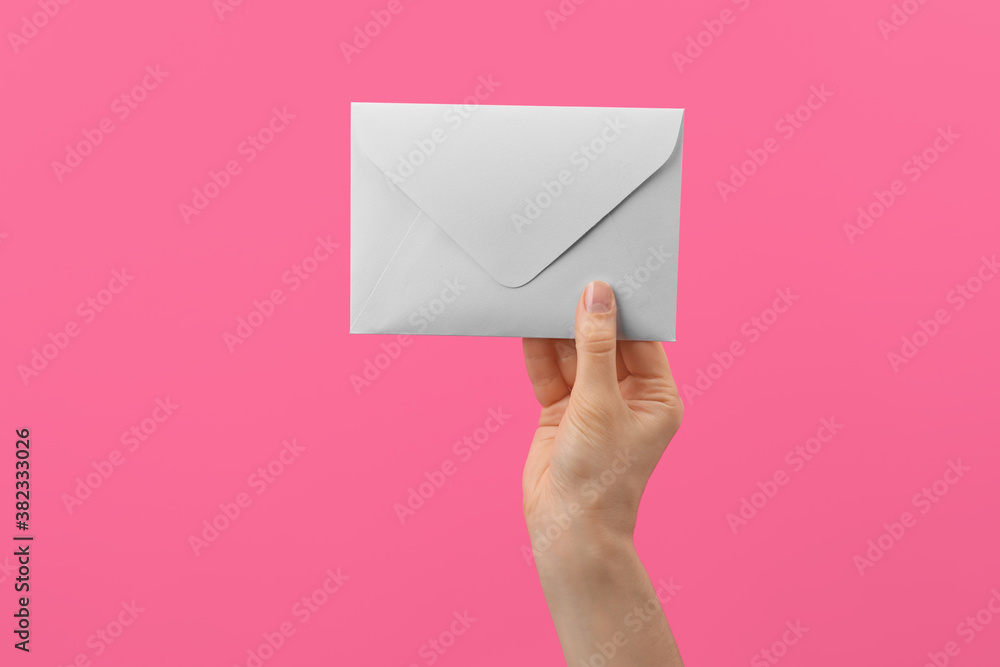 Woman holding white paper envelope on pink background, closeup