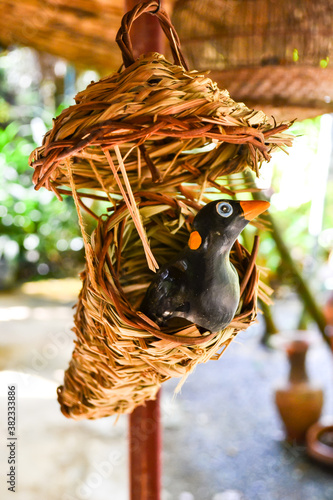 The fake bird lives in a beautiful wooden nest.