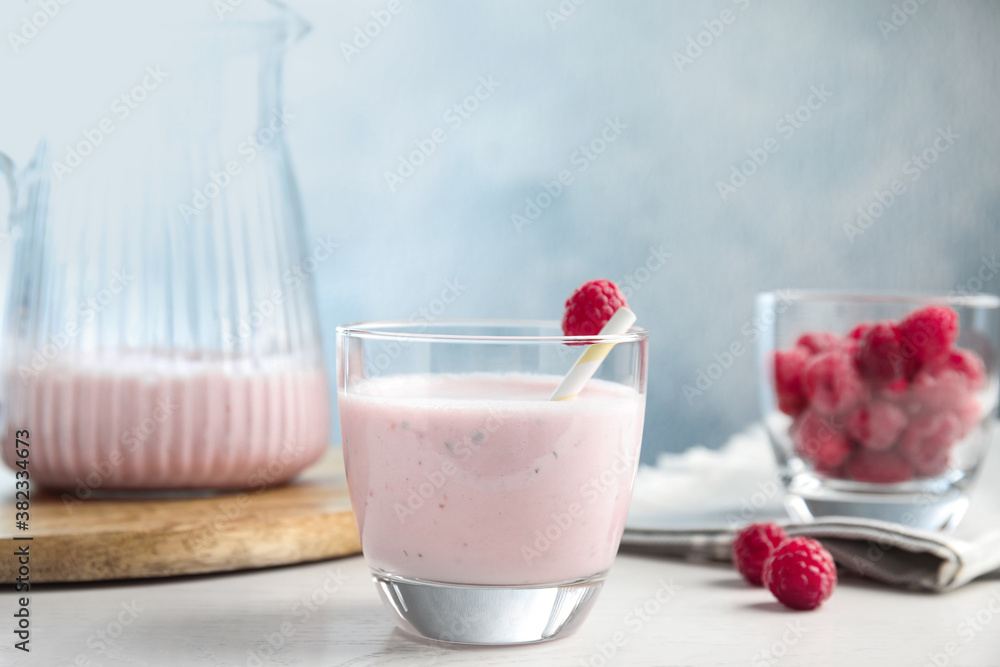 Tasty fresh milk shake with raspberry on white table Tasty fresh milk shake with raspberry on white table