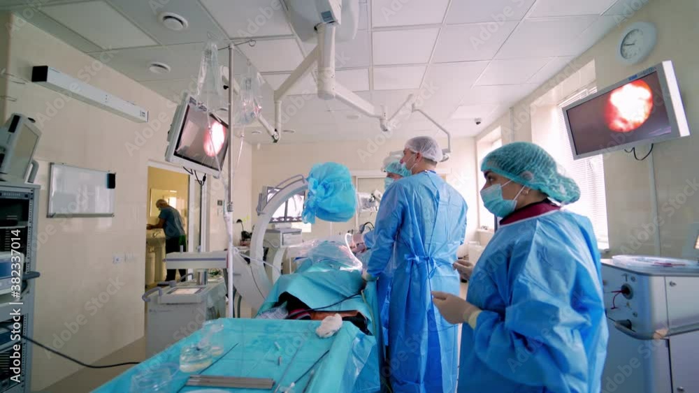 Surgery in the operating room. Modern medical equipment in the hospital. Teamwork of doctors doing an operation to a patient and look at medical monitors. Surgery in the operating room. Modern medical equipment in the hospital. Teamwork of doctors doing an operation to a patient and look at medical monitors.