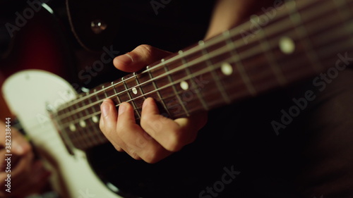 Musician playing electric guitar in studio. Guitarist hand pinching chords