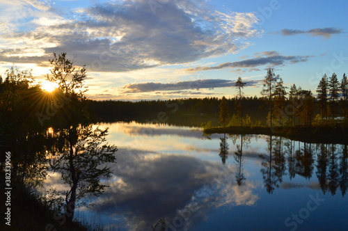Late summers evening in Finland. Sunset on the lake  Haltiaj  rvi  Salla. Calm water  cloudlets in the sky  the last rays of the setting sun.