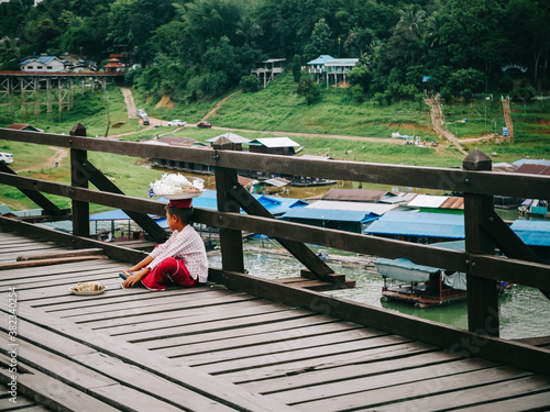 фотографія KANCHANABURI,THAILAND 6 july 2020 - many Mon children sit on the Sapan mon bridge,located in Sangkhlaburi District,Sangkhla Buri is in the far west of the province