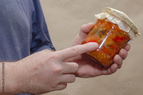 Male hands hold a glass jar of canned food. photo