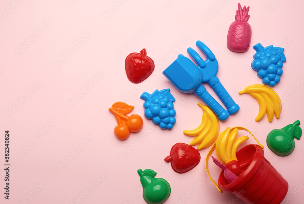 plastic childrens toys in the form of fruit and a bucket on a pink background plastic childrens toys in the form of fruit and a bucket on a pink background