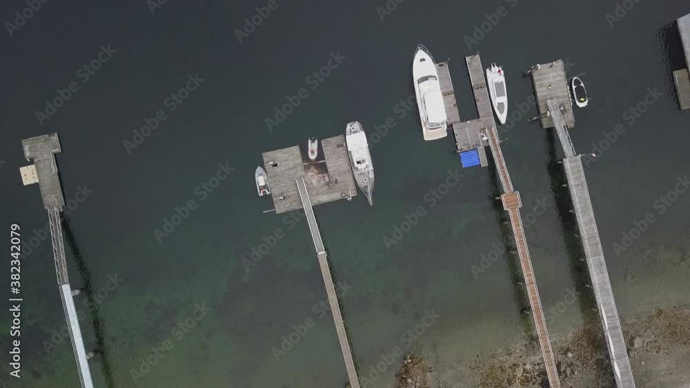 Dock or pier from above in bird's eye view. Big and small boats anchoring. Raising and circulating drone aerial top down shot. clear pacific waters and some rocks under the surface. Dock or pier from above in bird's eye view. Big and small boats anchoring. Raising and circulating drone aerial top down shot. clear pacific waters and some rocks under the surface.