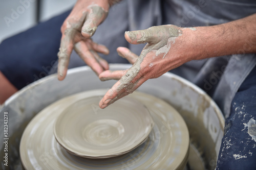 Detail with hands of an artist modeling a bowl on a pottery wheel
