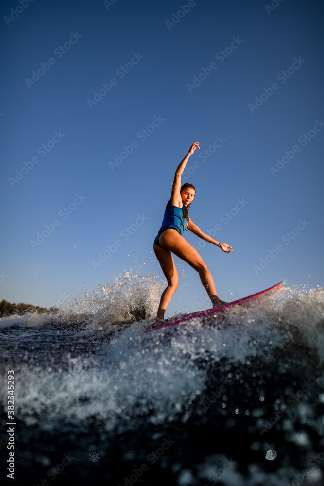 Young attractive woman vigorously rides the wave on surf style wakeboard