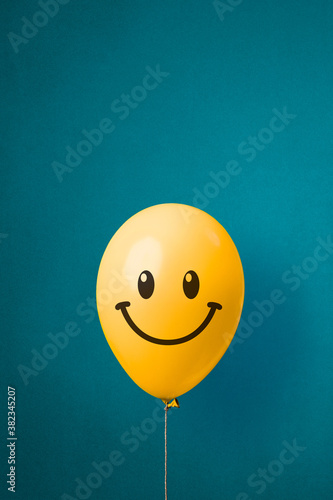 Stock photo of a yellow balloon with smiley face on a blue background photo