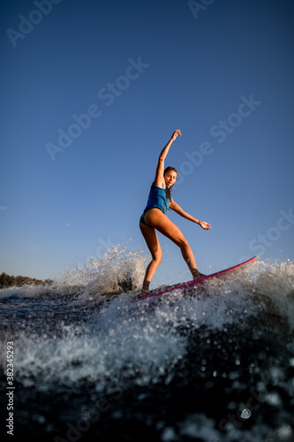 Young attractive woman vigorously rides the wave on surf style wakeboard