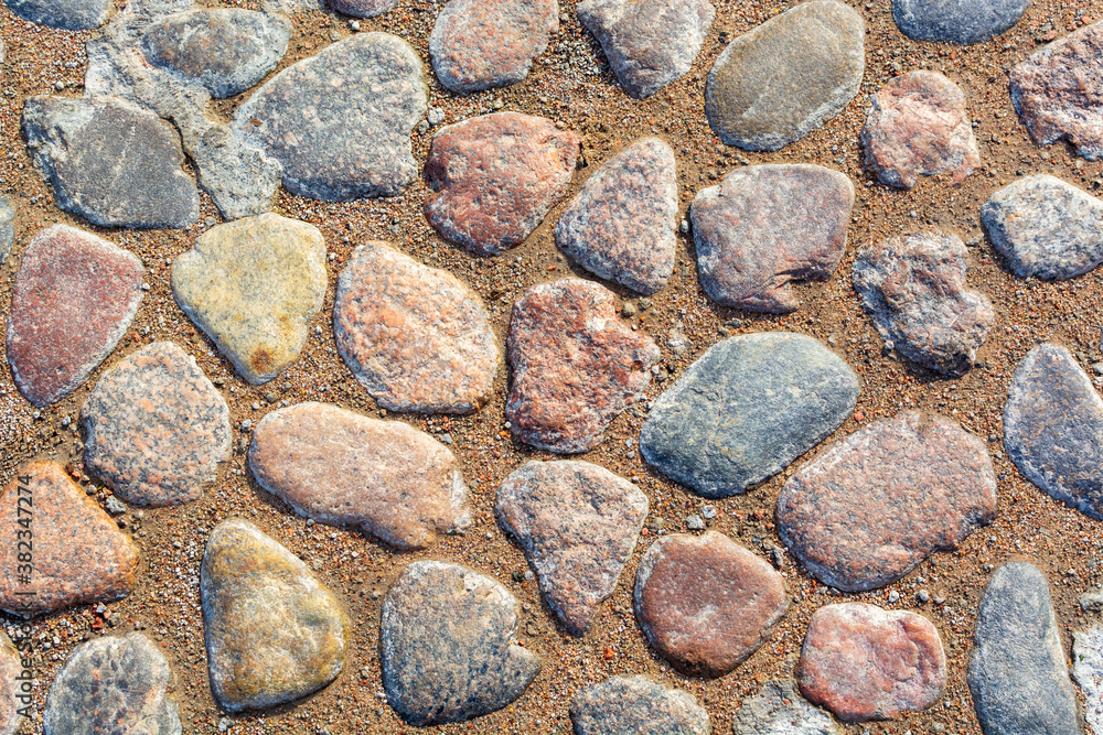 Flat sea cobblestones on a sandy beach. Rounded stones with different form background cut out. Large rocks mosaic wallpaper with different size and color texture. Mineral material edge curves top view Flat sea cobblestones on a sandy beach. Rounded stones with different form background cut out. Large rocks mosaic wallpaper with different size and color texture. Mineral material edge curves top view