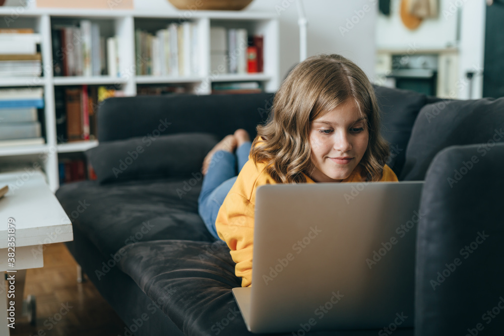 young girl laying on sofa and using laptop computer in her living room young girl laying on sofa and using laptop computer in her living room