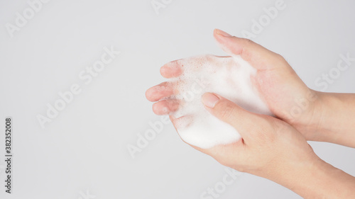 Hands washing gesture with foaming hand soap on white background.