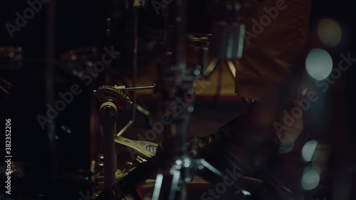 Closeup drum pedal in action in concert hall. Musician using drum set indoor.