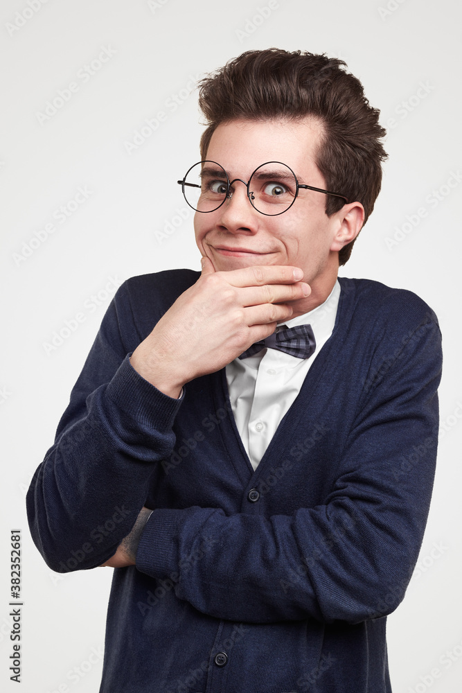 Pondering young man in elegant outfit rubbing chin Pondering young man in elegant outfit rubbing chin