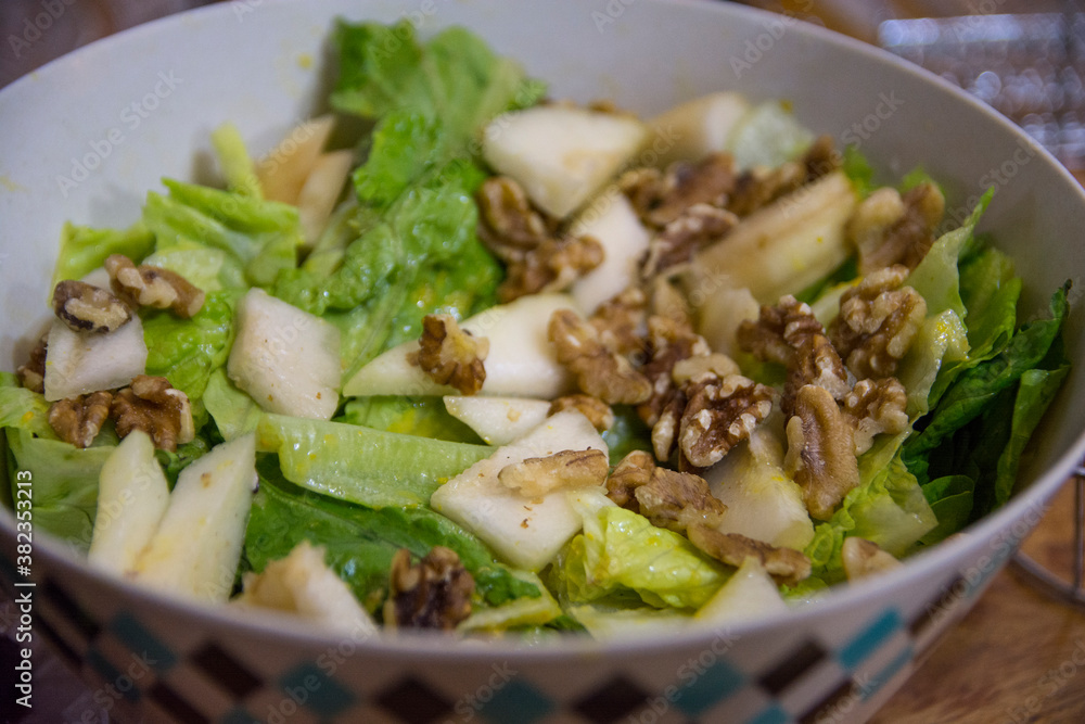 Lettuce salad with Persian walnuts, and slices of apples, served in a bowl Lettuce salad with Persian walnuts, and slices of apples, served in a bowl