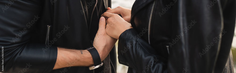 Website header of young couple in leather jackets holding hands outdoors