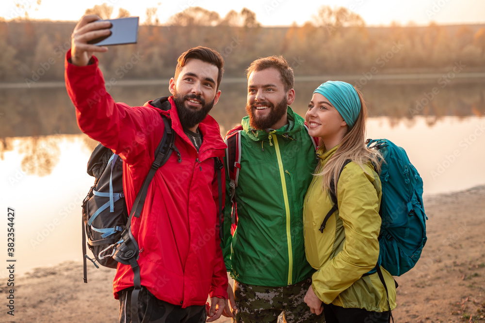 Young hikers taking selfie near river