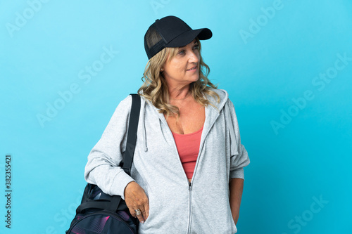 Middle aged sport woman over isolated background looking to the side and smiling