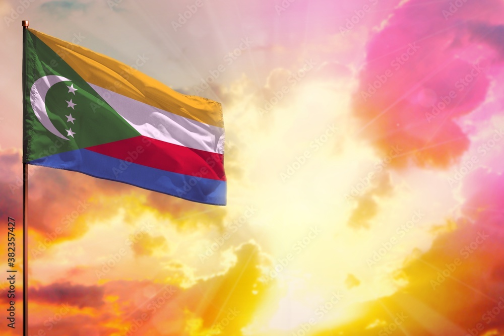 Fluttering Comoros flag in top left corner mockup with the space for your text on beautiful colorful sunset or sunrise background.