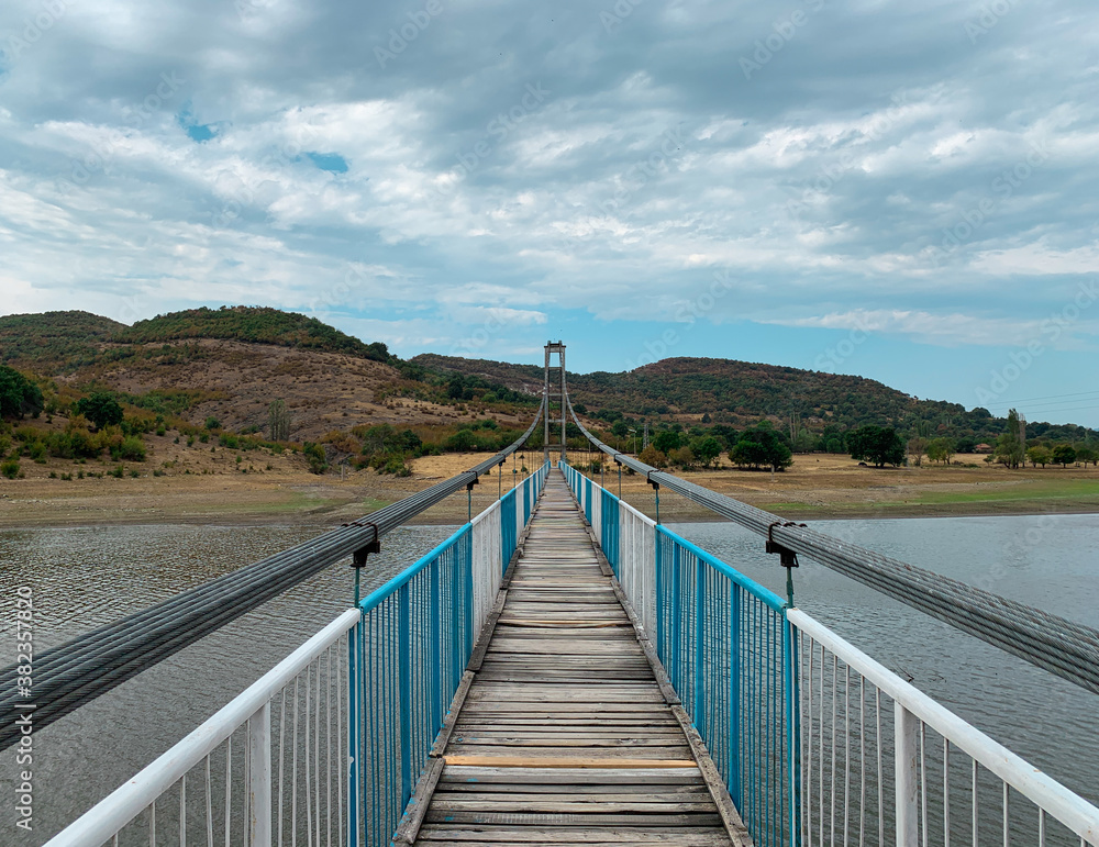 Pedestrian cable suspension bridge over waters of Studen Kladenets dam leading to the Lisitsite village in Bulgaria