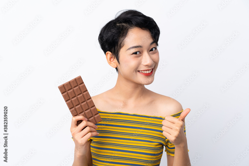 Young Asian girl taking a chocolate tablet and with thumb up Young Asian girl taking a chocolate tablet and with thumb up