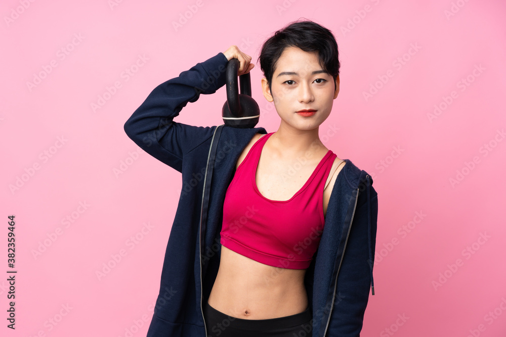 Young sport Asian woman over isolated pink background making weightlifting with kettlebell Young sport Asian woman over isolated pink background making weightlifting with kettlebell