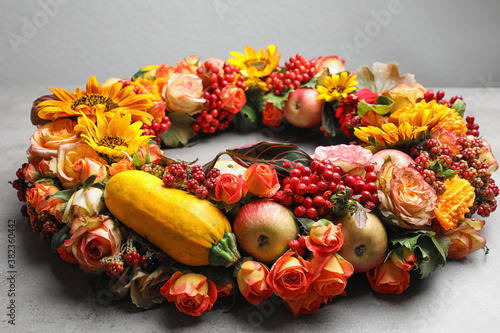 Fototapeta Naklejka Na Ścianę i Meble -  Beautiful autumnal wreath with flowers, berries and fruits on light grey background, closeup